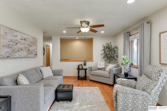 living room with ceiling fan, a textured ceiling, and light hardwood / wood-style flooring