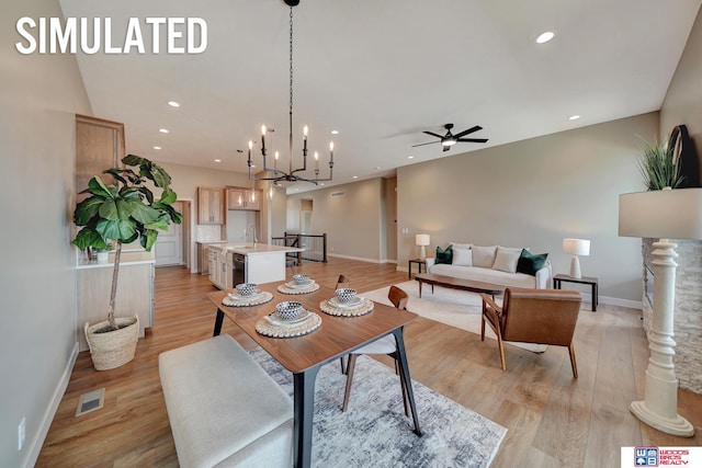 dining area with ceiling fan with notable chandelier, light hardwood / wood-style floors, and sink