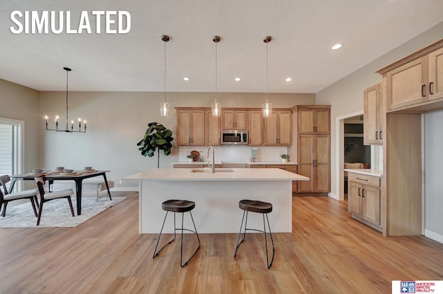 kitchen with tasteful backsplash, a kitchen island with sink, sink, and decorative light fixtures