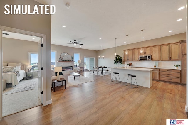 kitchen featuring a kitchen bar, an island with sink, hanging light fixtures, and light wood-type flooring