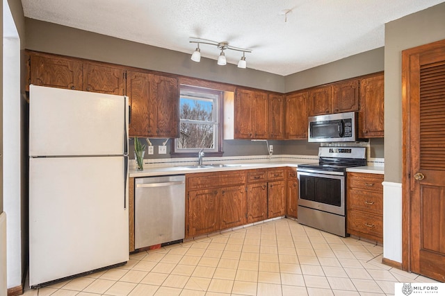 kitchen with a textured ceiling, appliances with stainless steel finishes, and sink