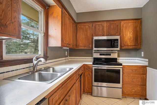 kitchen featuring a textured ceiling, stainless steel appliances, and sink