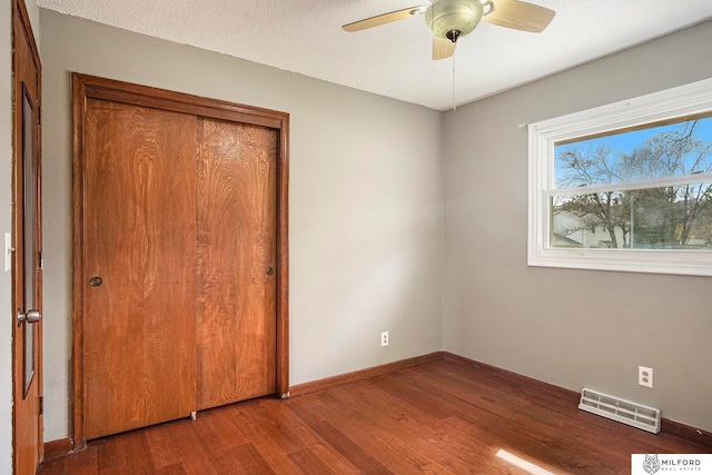 unfurnished bedroom featuring a closet, ceiling fan, hardwood / wood-style flooring, and a textured ceiling