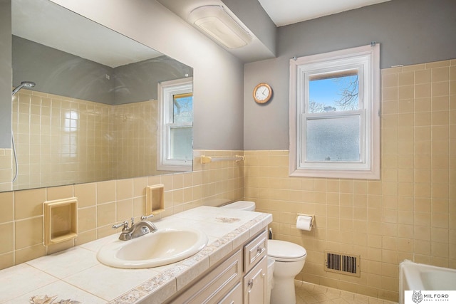 full bathroom featuring tile walls, vanity, tiled shower / bath combo, tile patterned flooring, and toilet