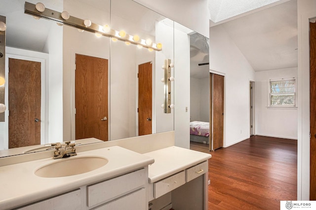 bathroom featuring vaulted ceiling, vanity, and hardwood / wood-style flooring