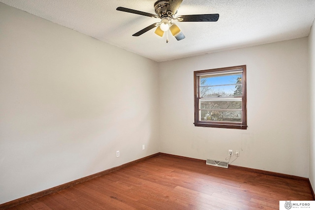 spare room with ceiling fan, a textured ceiling, and wood-type flooring