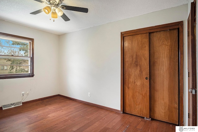 unfurnished bedroom with a closet, ceiling fan, hardwood / wood-style flooring, and a textured ceiling