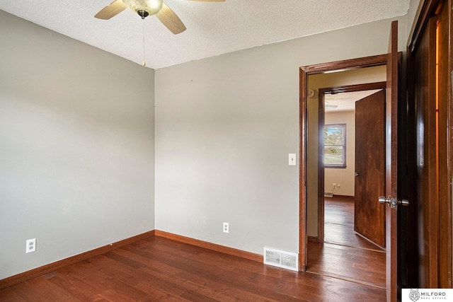 empty room with a textured ceiling, dark hardwood / wood-style flooring, and ceiling fan