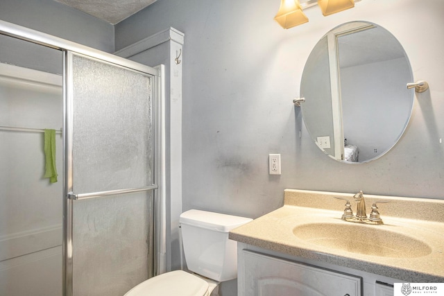 bathroom with a textured ceiling, a shower with door, vanity, and toilet