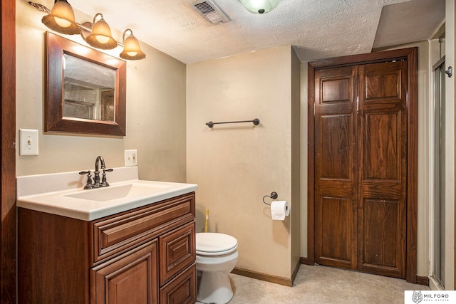 bathroom featuring a textured ceiling, vanity, and toilet