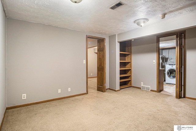 unfurnished bedroom featuring a textured ceiling, light carpet, and washer / dryer