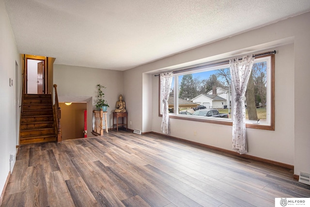 unfurnished living room featuring wood-type flooring and a textured ceiling