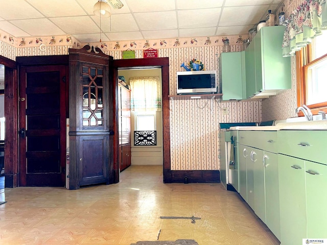 kitchen featuring light parquet floors, green cabinets, sink, and a paneled ceiling