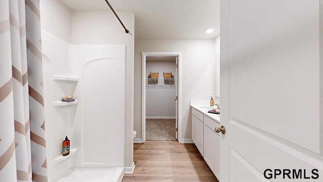 bathroom with walk in shower, vanity, toilet, and wood-type flooring