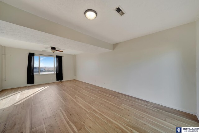 unfurnished room featuring a textured ceiling, ceiling fan, and light hardwood / wood-style flooring