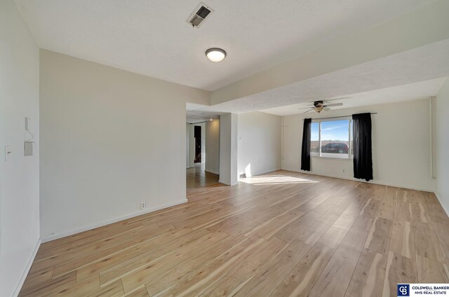 empty room with ceiling fan and light hardwood / wood-style flooring