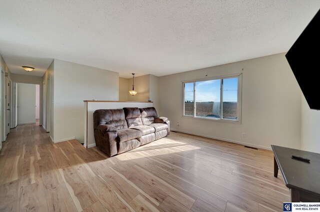 living room with light wood-type flooring and a textured ceiling