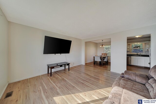 living room with sink, a chandelier, and light hardwood / wood-style floors