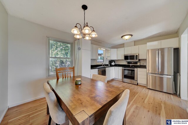 dining room with light hardwood / wood-style flooring, an inviting chandelier, and sink