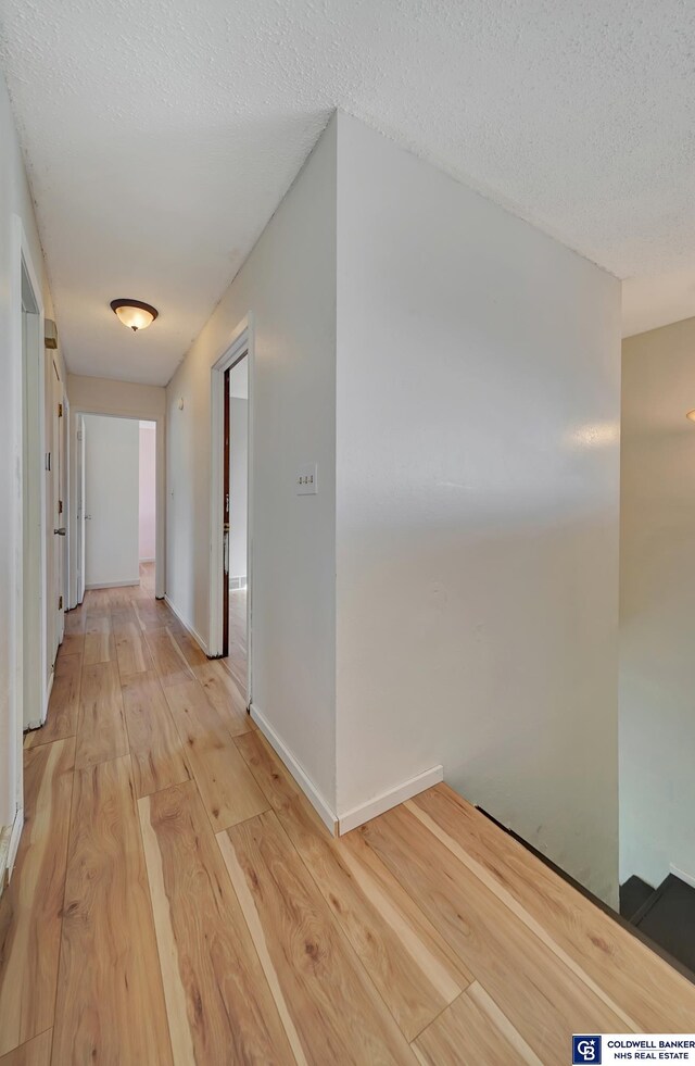 corridor featuring light hardwood / wood-style floors and a textured ceiling