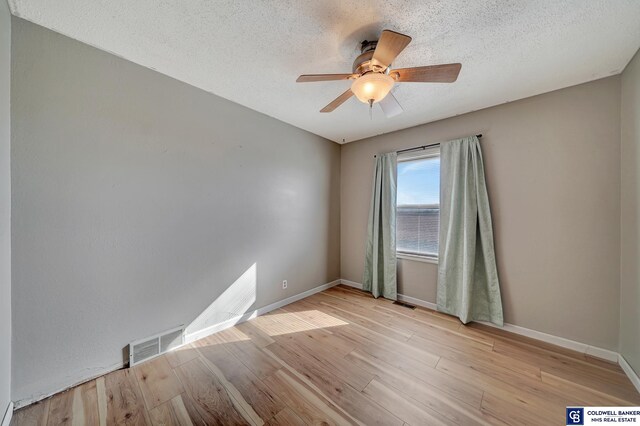 empty room with a textured ceiling, ceiling fan, and light hardwood / wood-style flooring