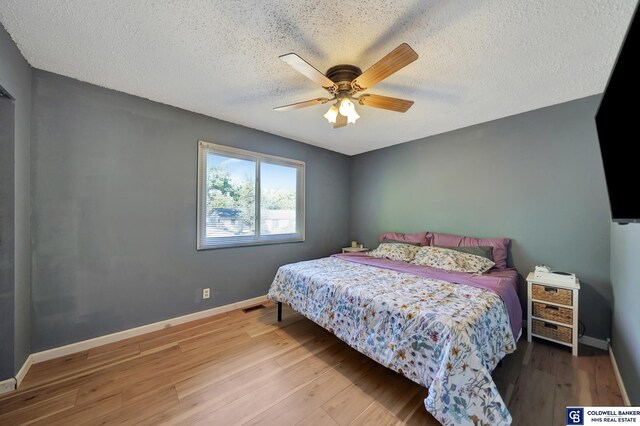 bedroom with light hardwood / wood-style floors, ceiling fan, and a textured ceiling