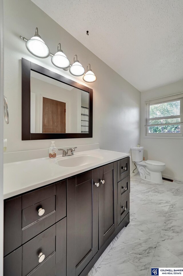 bathroom with vanity, toilet, and a textured ceiling