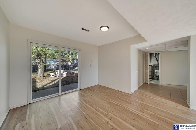 spare room featuring light wood-type flooring and water heater