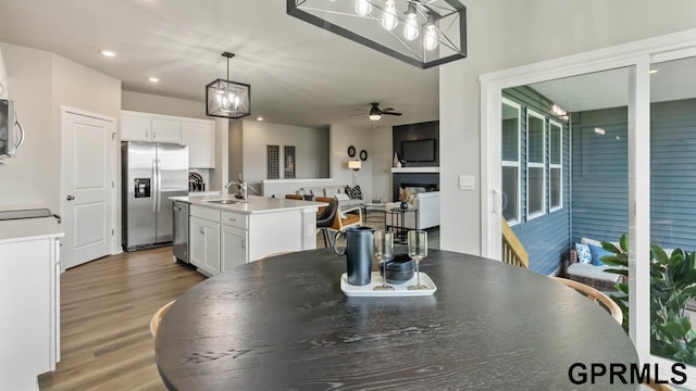 dining area with ceiling fan with notable chandelier, dark hardwood / wood-style floors, and sink