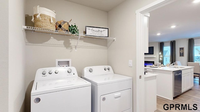 laundry area with light wood-type flooring, sink, and washing machine and dryer