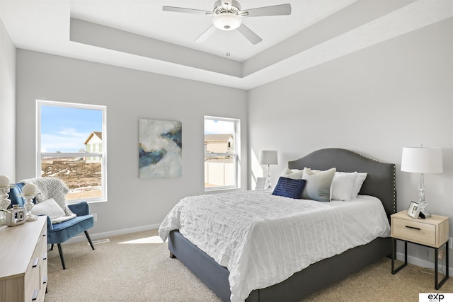 bedroom with a ceiling fan, visible vents, light colored carpet, baseboards, and a raised ceiling