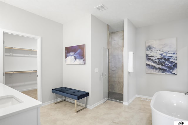 full bath with visible vents, a freestanding tub, a stall shower, a sink, and baseboards