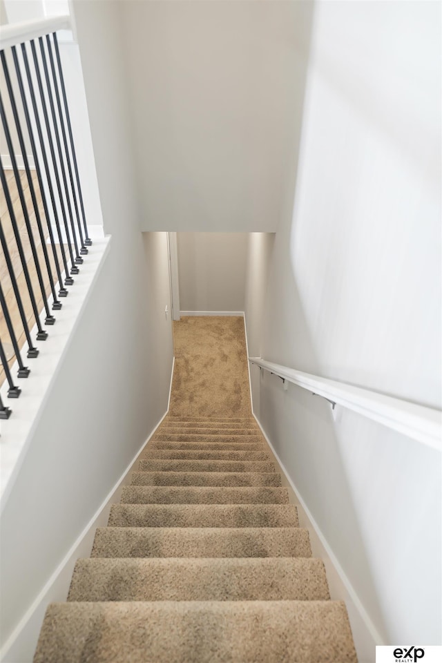 stairway featuring baseboards and carpet floors
