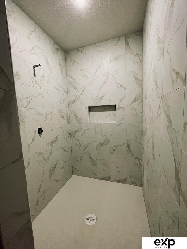 bathroom featuring a tile shower and a textured ceiling