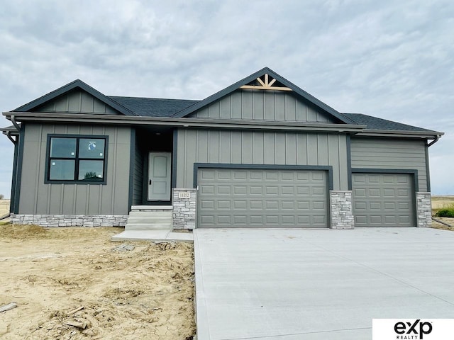 view of front of property featuring an attached garage, driveway, and stone siding