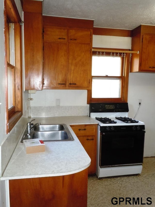 kitchen with a textured ceiling, white gas stove, and sink