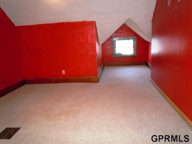 additional living space featuring lofted ceiling and light colored carpet