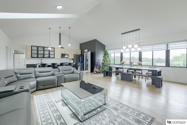 living room featuring a notable chandelier, lofted ceiling, light wood-type flooring, and sink