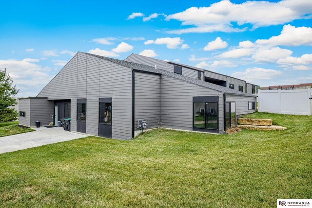 back of house with a lawn and a patio