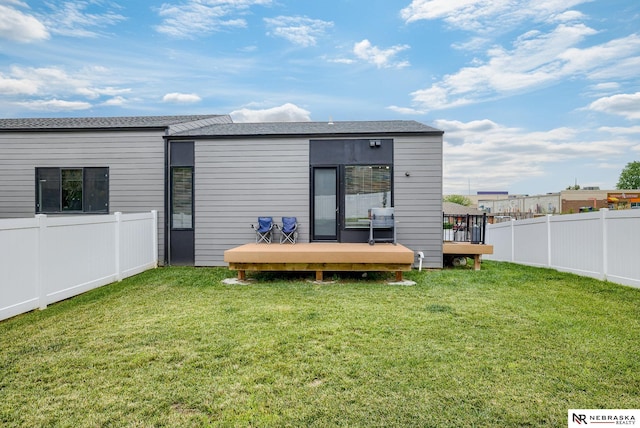 rear view of house featuring a lawn and a deck