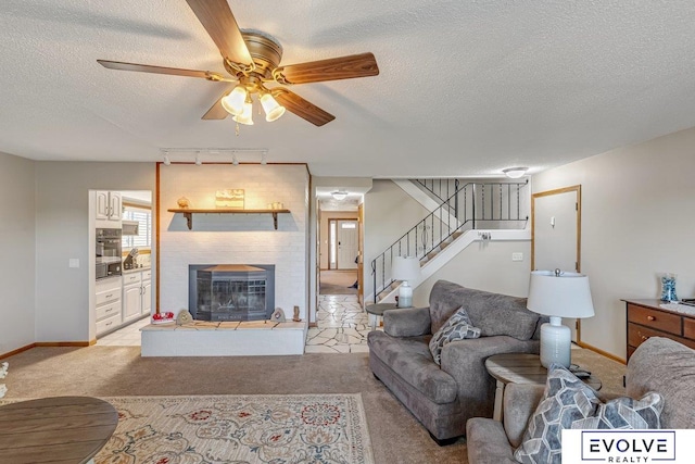 carpeted living room featuring ceiling fan, a textured ceiling, rail lighting, and a large fireplace