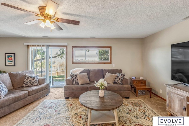 living room featuring ceiling fan, a textured ceiling, and light carpet