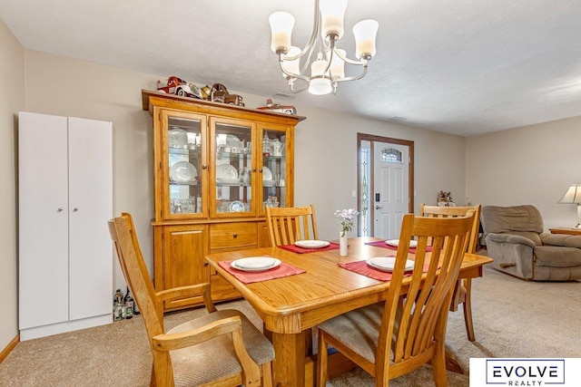 carpeted dining area featuring a textured ceiling and a chandelier