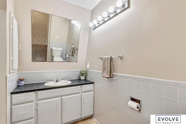 bathroom with vanity, tile walls, and toilet