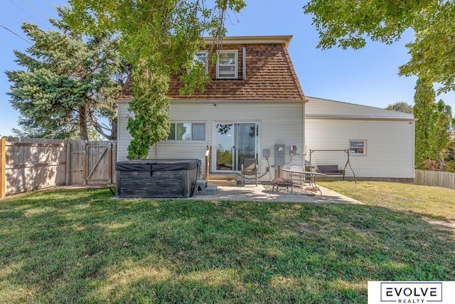 rear view of house with a yard, a patio area, and a hot tub