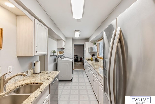 kitchen with light stone countertops, white cabinets, appliances with stainless steel finishes, and sink