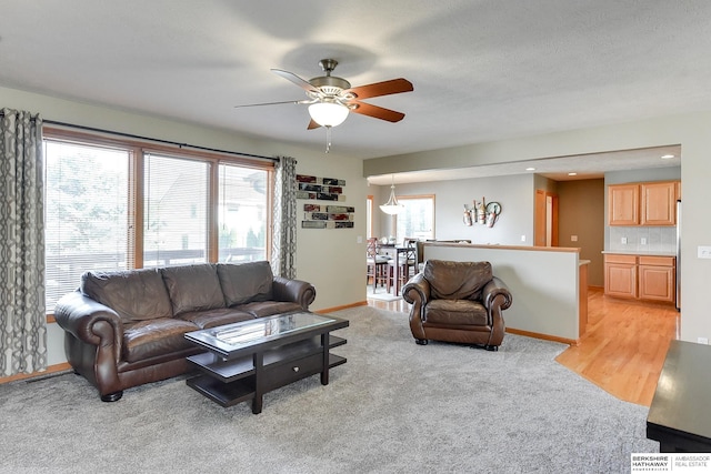 carpeted living room with a textured ceiling, ceiling fan, and a wealth of natural light