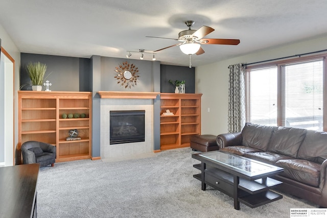 living room featuring a tile fireplace, ceiling fan, and light colored carpet