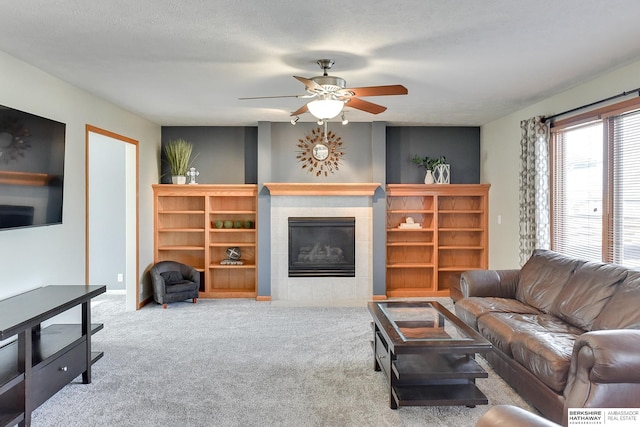 carpeted living room with ceiling fan, a textured ceiling, and a fireplace