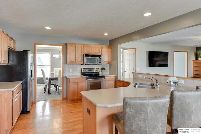 kitchen featuring appliances with stainless steel finishes, light brown cabinetry, light wood-type flooring, and sink